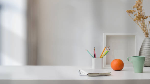 istock Close up view of  workspace with copy space, stationery, coffee cup, and decorations on white table with blurred background 1199381583