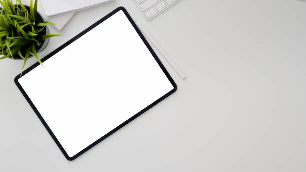 istock Top view of workplace with blank screen tablet, copy space, office supplies and tree pot on withe desk 1199381725