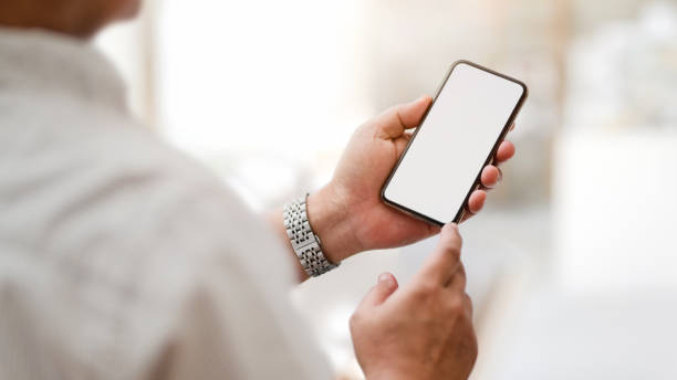 istock Cropped shot of  texting  blank screen smartphone with blurred office room 1199381784