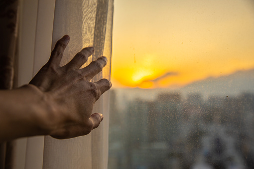 Close-up hand open window curtain in the morning