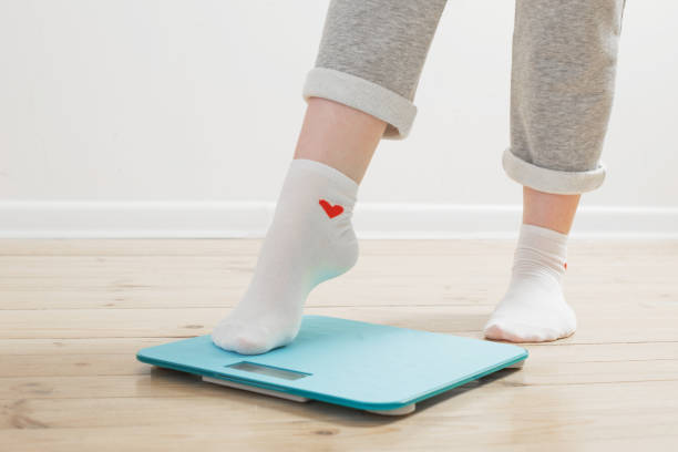 female legs on electronic scales on a wooden floor stock photo