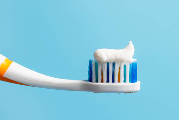 istock Toothbrush with white toothpaste close-up on blue background 1199384854