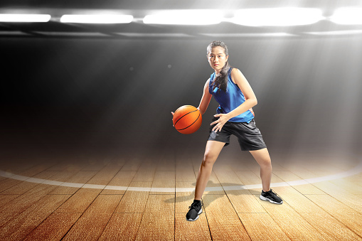 Asian woman basketball player in action with the ball on the indoor basketball court