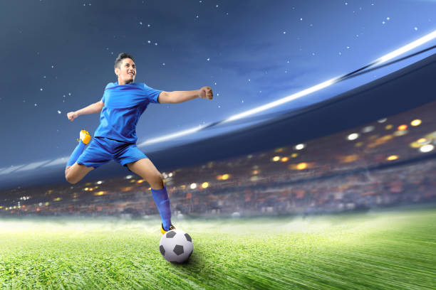 азиатский футболист пинает мяч на футбольном поле - indonesia football стоковые фото и изображения