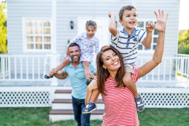 istock Parents having fun in front yard carrying children piggyback 1199391556
