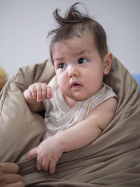 istock Adorable baby with messy hair look for something while sit in a couch . 1199392981