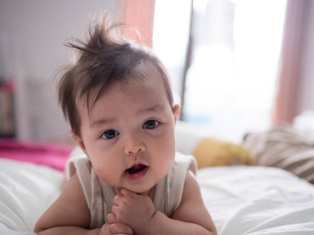 istock Adorable baby with curious face lying on bed. 1199393078