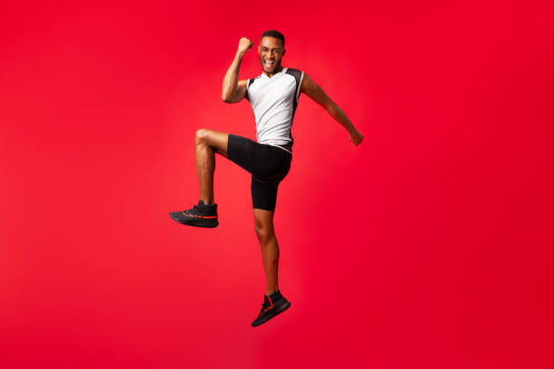 istock Full length afro guy celebrating success jumping at studio 1199394868