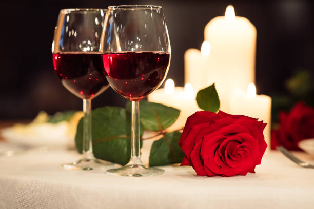 istock Two Red Wine Glasses And Rose Lying On Restaurant Table 1199396055