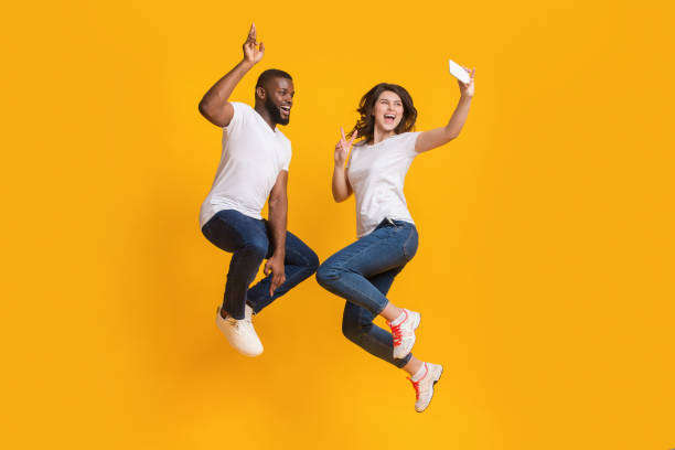 istock Cheerful Interracial Couple Taking Selfie While Jumping In Air 1199396645