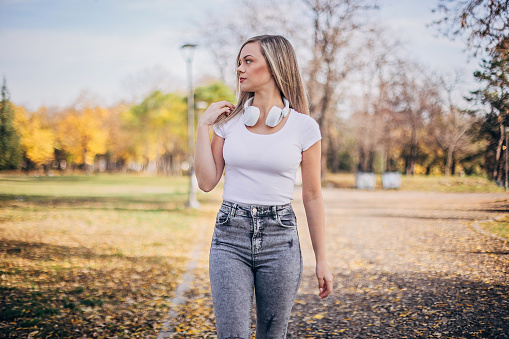 Beautiful young woman is walking in the park on beautiful autumn day and enjoying life