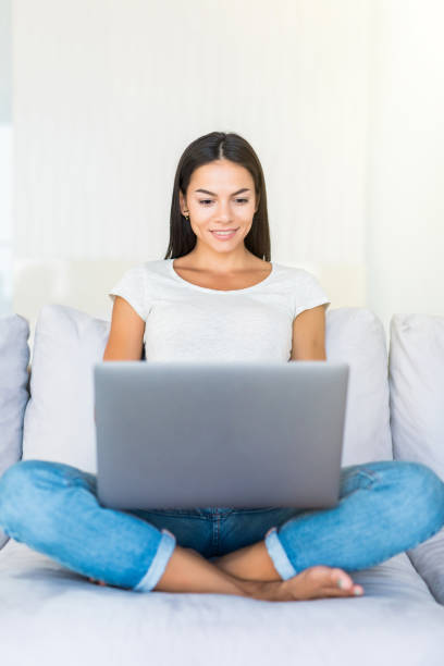 istock Smiling happy woman sitting on the sofa and using laptop. 1199398345