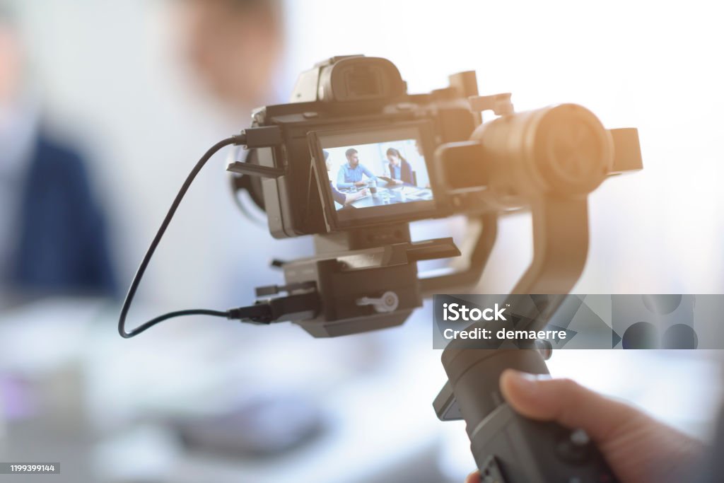 Professional videomaker shooting a video Professional videomaker shooting a video, defocused actors in the background, videomaking and communication concept Home Video Camera Stock Photo