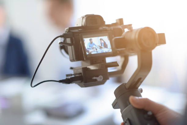 Professional videomaker shooting a video Professional videomaker shooting a video, defocused actors in the background, videomaking and communication concept reportage photos stock pictures, royalty-free photos & images