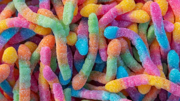 Photo of Pile of neon sugary gummy worms or  chewy sour crawlers background