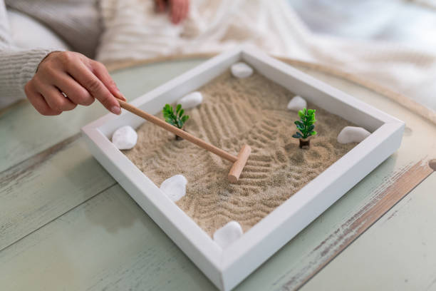 hand von schönen jungen frau mit ihrem zen-garten zu hause. schöne junge lächelnde frau entspannen mit ihrem zen-garten und genießen sie ihren tag - stone zen like buddhism pebble stock-fotos und bilder