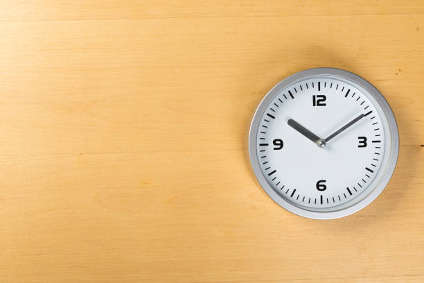 istock minimalist white wall clock with light metal on wooden background texture 1199400771