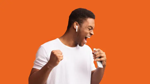 Photo of Portrait of black man in wireless headphones singing