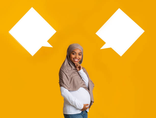 istock Pregnant afro muslim woman over background with two empty speech bubbles 1199401117
