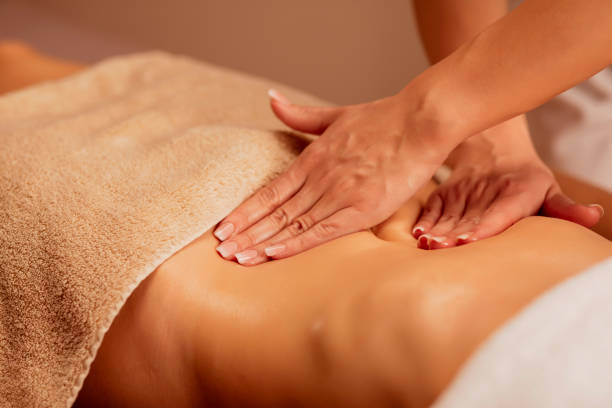 istock Belly massage. Anti cellulite massage.  Massage Therapist doing healing massage with rolling pin or battledore . Woman enjoying in relaxing massaging at health spa treatment. 1199403335