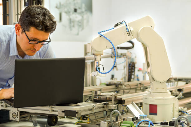 istock Engineer is working on laptop to program robot arm and smart factory automation 1199405058