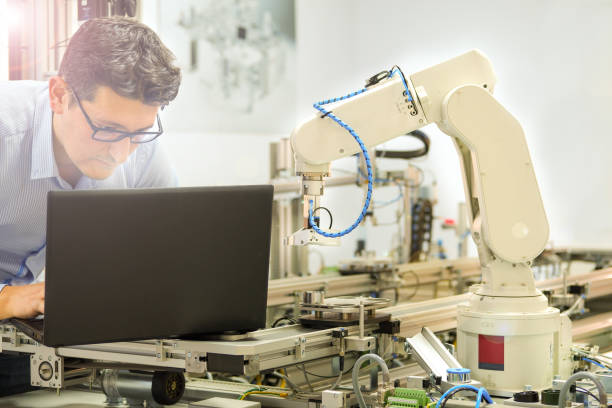 istock Engineer is working on laptop to program robot arm and smart factory automation 1199405059
