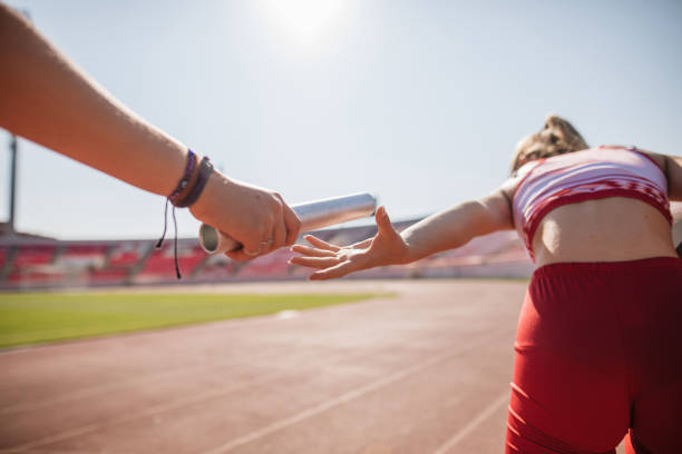 istock Young female athletics exchanging relay baton 1199409855