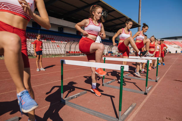 istock Hardworking teenage athletes hurdling on training 1199410355