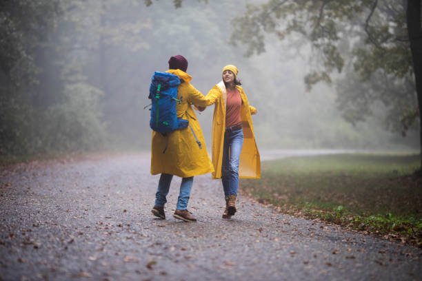 istock Happy couple in raincoats having fun in misty forest. 1199412416