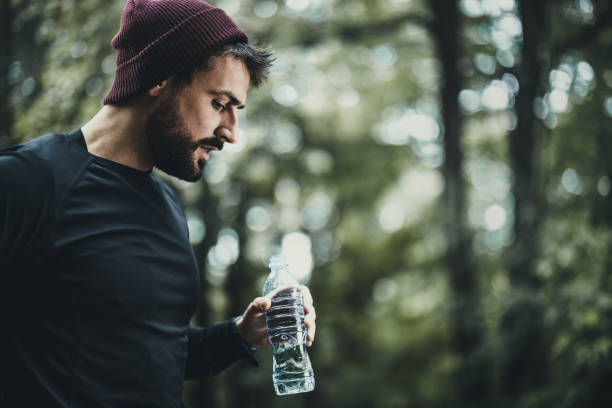 istock Exhausted athletic man having a water break in nature. 1199413283