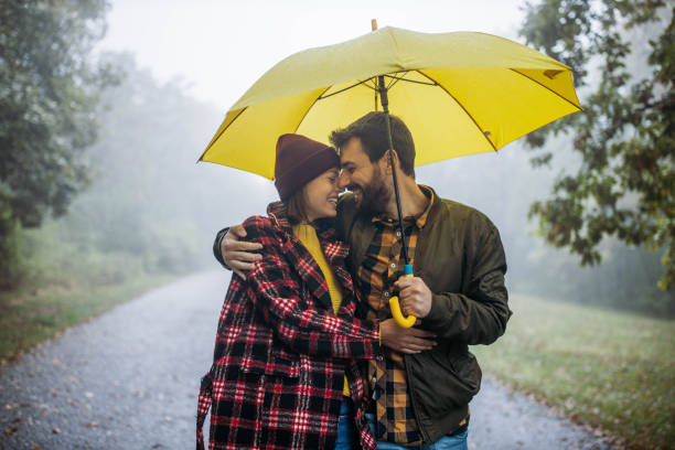 istock Happy embraced couple taking a walk on a rainy day at forest. 1199413873