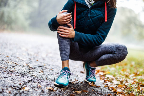 Unrecognizable athlete holding her knee in pain at the park. Unrecognizable athletic woman feeling pain in her knee at the park. Copy space. human knee stock pictures, royalty-free photos & images