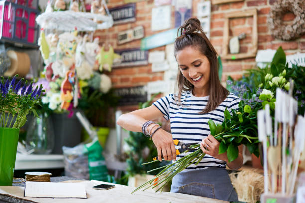 alegre florista joven corte de flores para ramo en el mostrador - florist fotografías e imágenes de stock