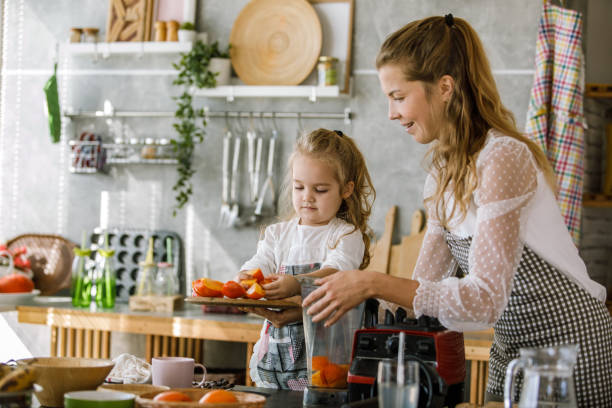 istock Mother and her toddler daughter adding freshly cut persimmons into a blender 1199422041