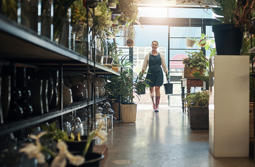 Full length shot of an attractive young florist carrying buckets while working inside her plant nursery