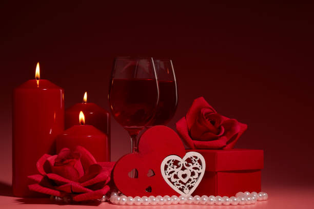 istock Gift boxes, two glasses with wine, burning candles, red roses and hearts on red background. Valentine's day. Wedding day. 1199422844