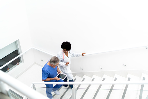 Mujer doctora y enfermera masculina subiendo en la escalera en el hospital photo