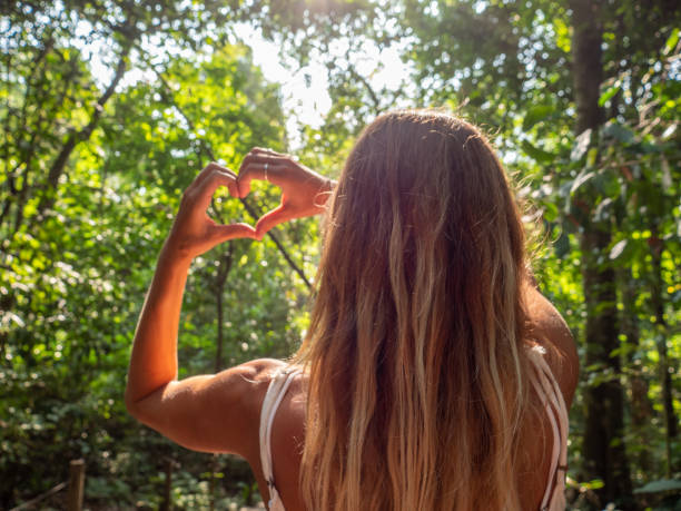 istock Young woman making heart shape finger frame in tropical rainforest 1199426041