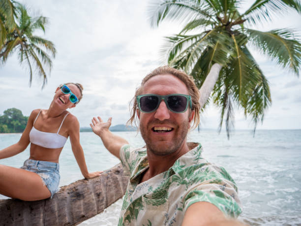 istock Young couple taking selfie on palm tree on tropical beach 1199426402