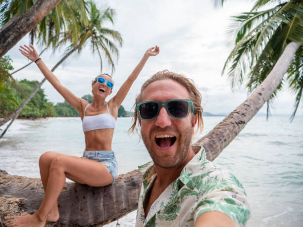 istock Young couple taking selfie on palm tree on tropical beach 1199426453