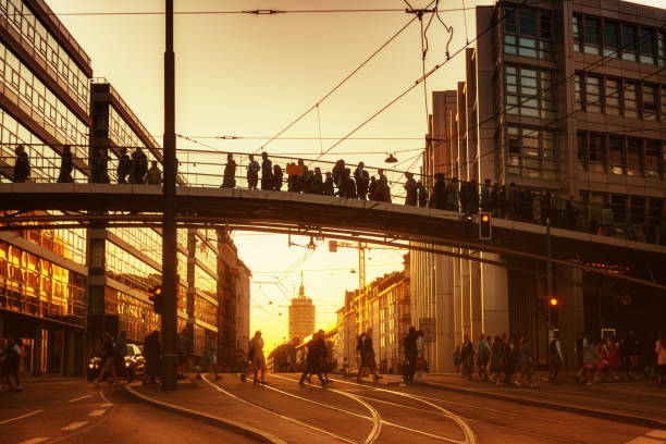people walking over pedestrian bridge in munich at sunset hour home from Beer Fest
