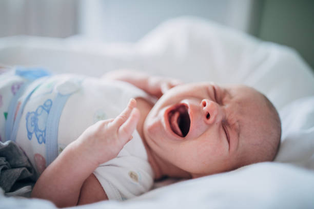 Baby boy lying on bed alone and crying.