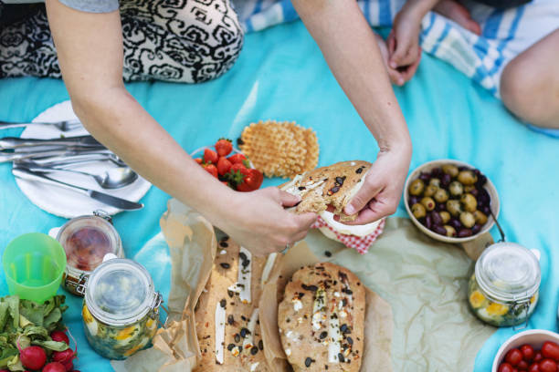 istock picnic on bright blue blanket: hands breaking bread 1199432643