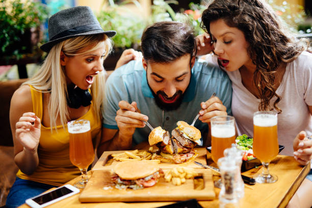 istock Young man eating oversized burger in a fast food restaurant 1199433404