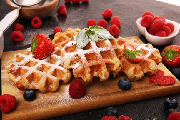 istock Traditional belgian waffles with fresh blueberries, sugar and raspberries on rustic table 1199433635