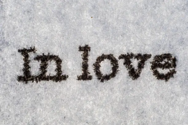 Photo of Extreme macro shot of the word in love typed on white paper. Grungy textured bloody mood.