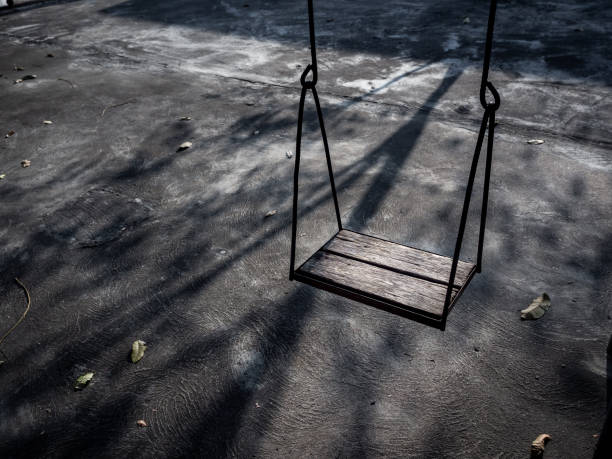 istock Old lonely wooden swing on sunset time with light and shadow. 1199434768