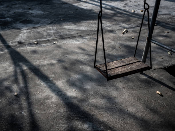 istock Old lonely wooden swing on sunset time with light and shadow. 1199434940