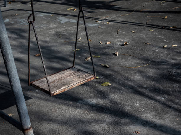 istock Old lonely wooden swing on sunset time with light and shadow. 1199434963