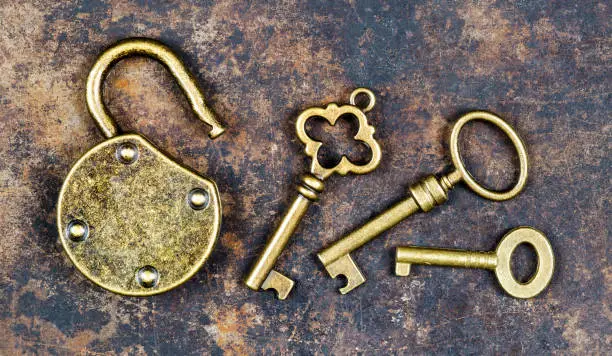 Photo of Keys and unlocked padlock on a rusty grunge metal background, escape room concept